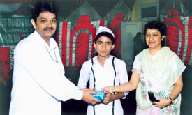 Rajan Sachdev presenting award to a student for academic excellence on Annual Day at Bal Ashram.